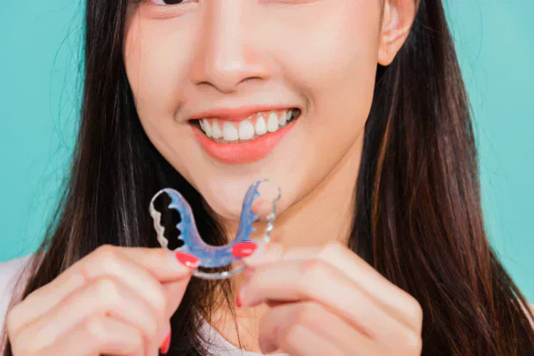 A girl holding Hawley retainers.