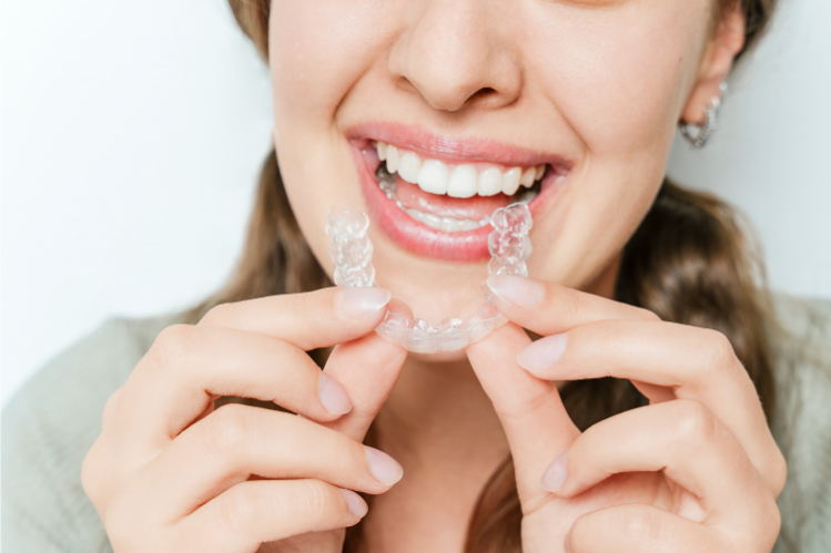 A girl is holding a clear aligner