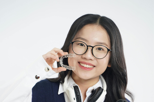 Girl smiling and confidently holding clear aligners