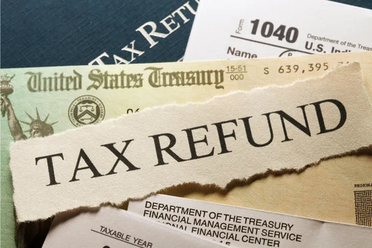 A couple of tax documents, a certificate, and a piece of paper with “Tax Refund” written.