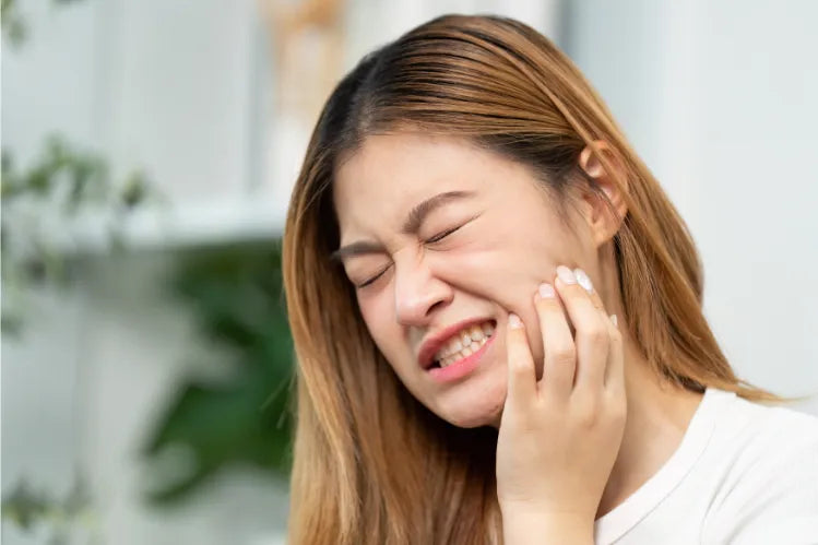 Young woman holding her jaw in pain.