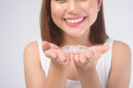 A woman showing a pair of clear aligners